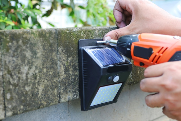 Human hand installing solar-powered motion sensor light